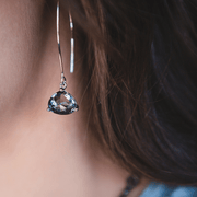 Teardrop-shaped gemstone earring worn by a person with blurred background