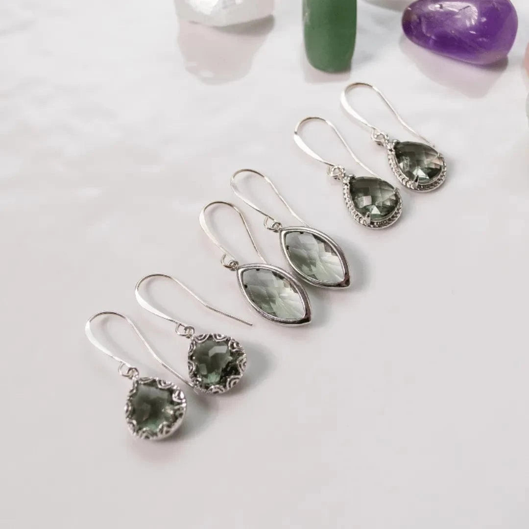 Set of silver earrings with green gemstones on a light background
