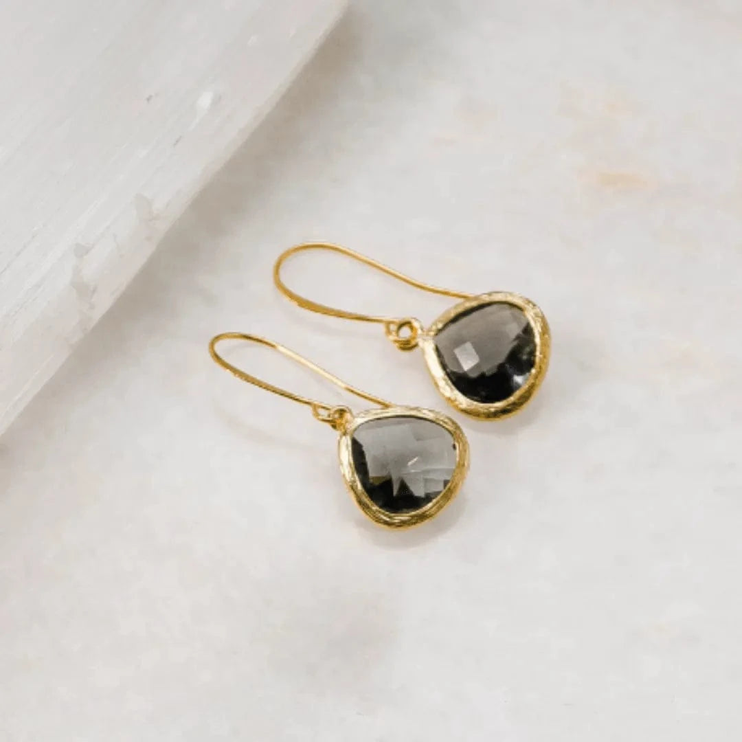 Gold earrings with smoky quartz stones on a light background