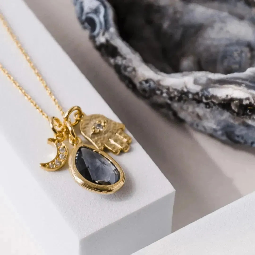 Gold plated hamsa hand necklace with crescent moon and dusk grey faceted glass teardrop