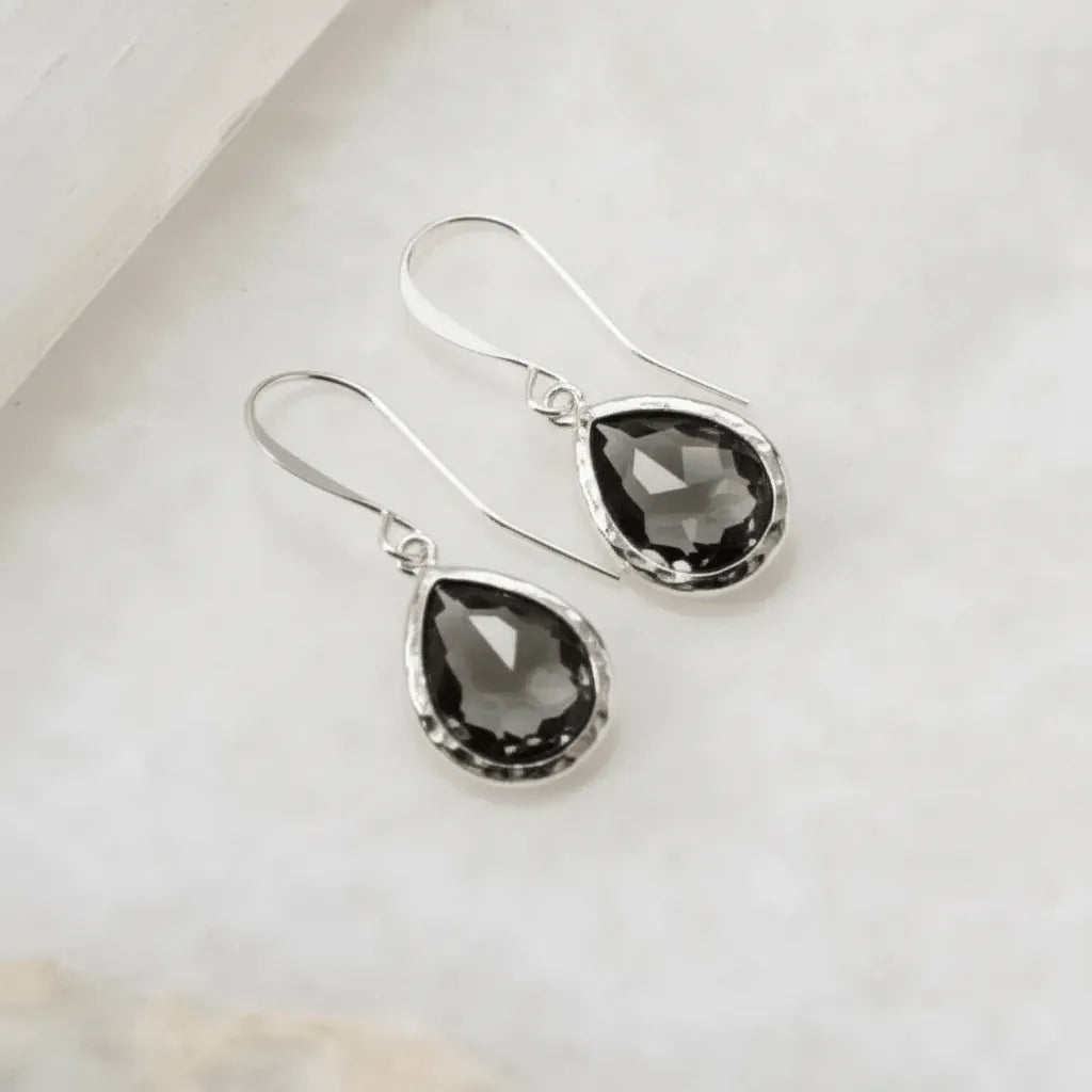 Silver teardrop earrings with black gemstones on a light background