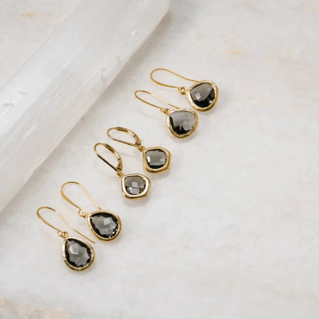 Gold earrings with gray gemstones on a light background