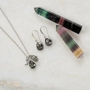 Jewelry set with necklace, earrings, and crystal on a light background