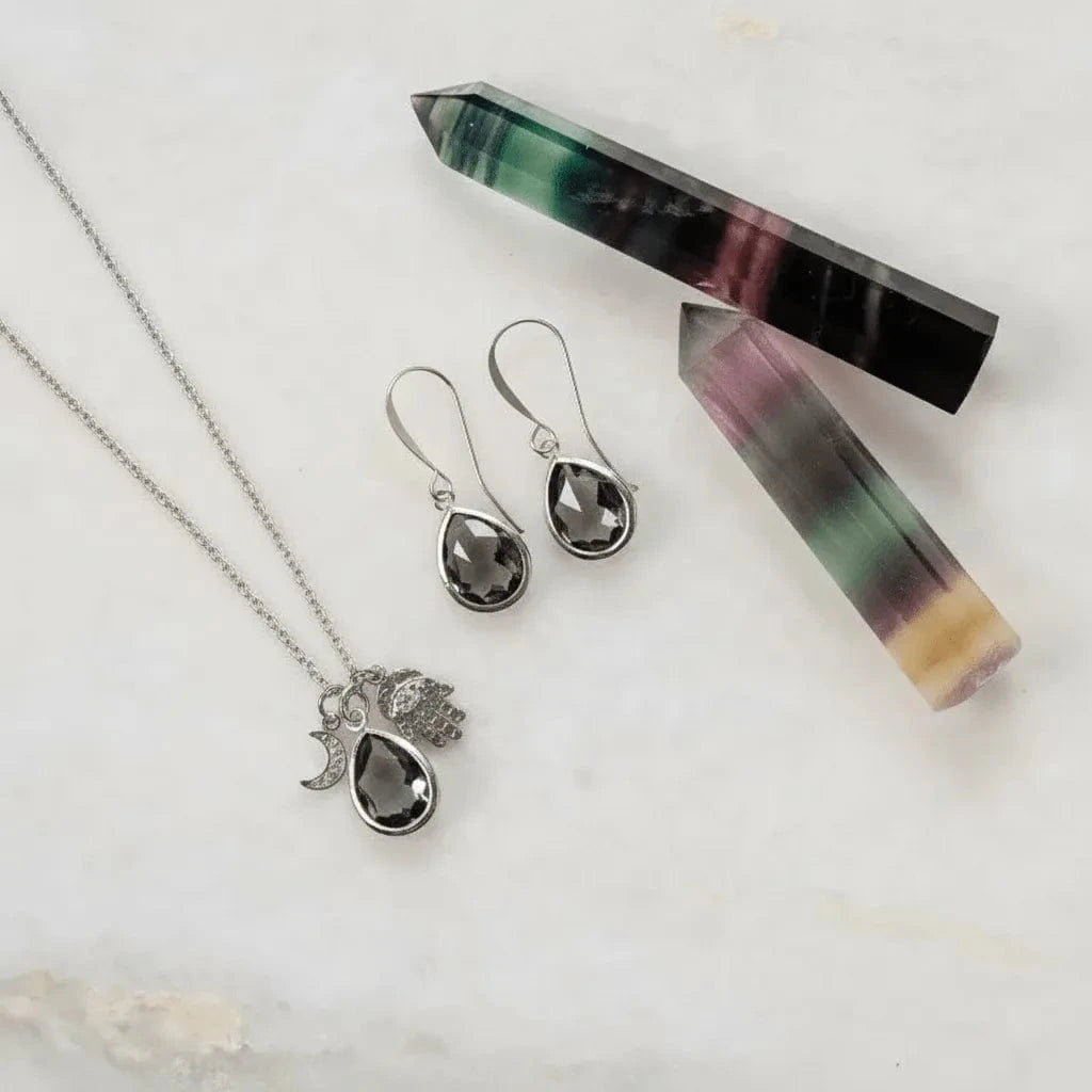 Jewelry set with necklace, earrings, and crystal on a light background