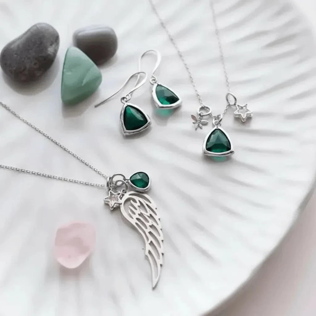 Jewelry set with green gemstones and silver accents on a white surface