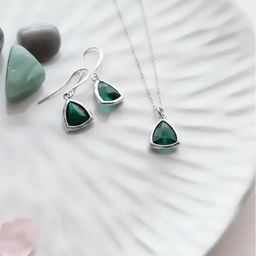 Jewelry set with green gemstones and silver accents on a white surface