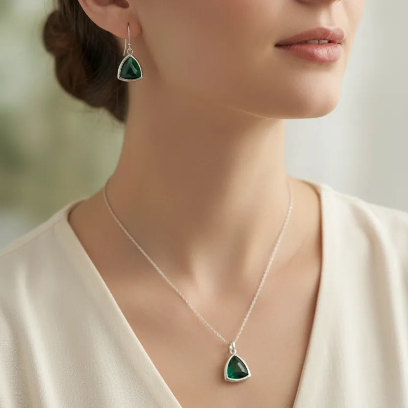 A close-up of a woman wearing a silver pendant necklace and matching drop earring