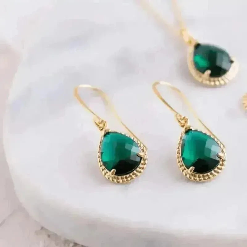 Gold earrings with green gemstones on a white background