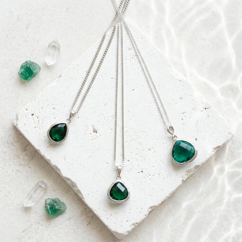 Three silver necklaces in emerald green faceted glass: Elegant Pebble, Mini Pebble and teardrop pendants, May birthstone colour