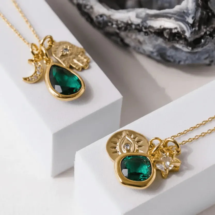 Gold necklaces with green gemstones on a white surface
