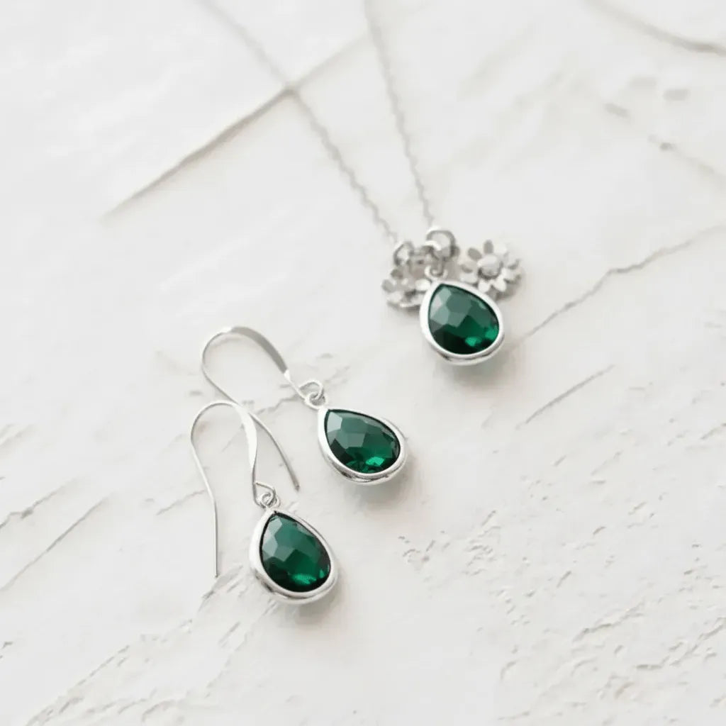 Silver earrings with green gemstones on a white textured surface