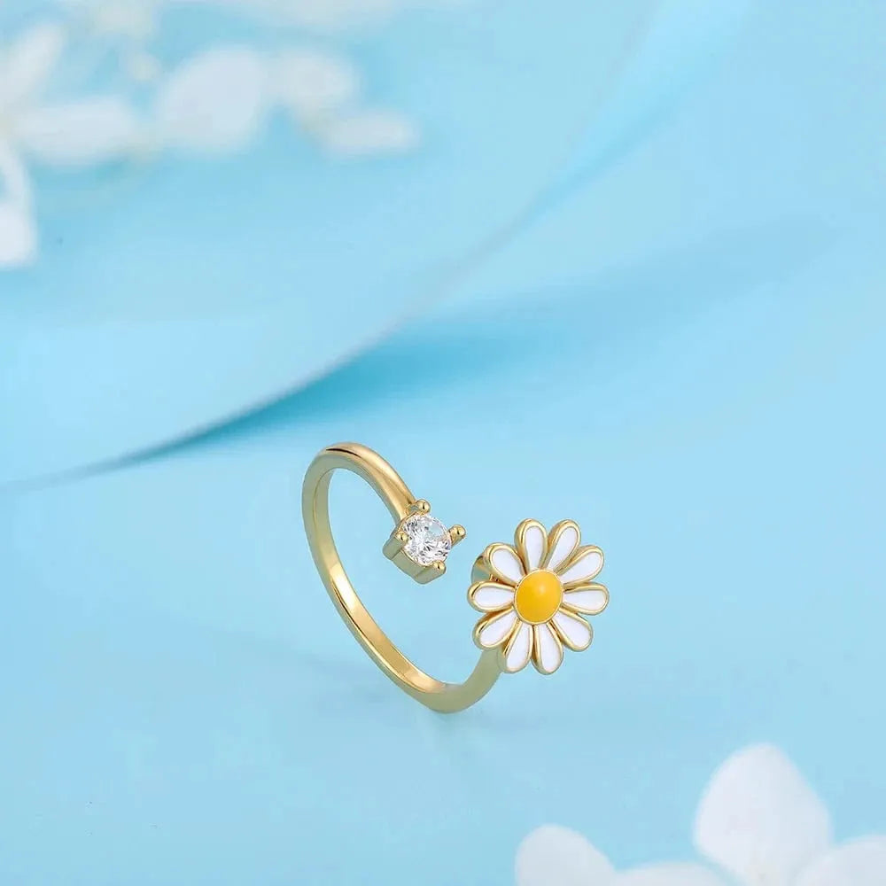 Gold ring with a daisy flower design on a light blue background