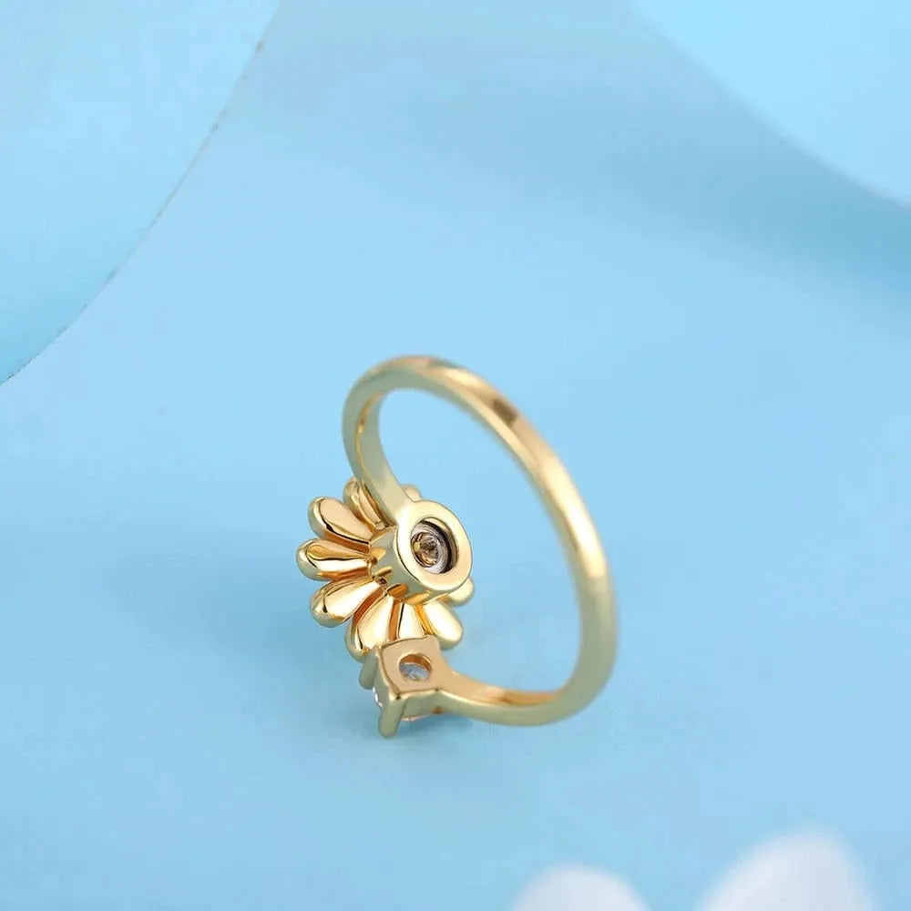 Gold ring with a sunflower design on a light blue background