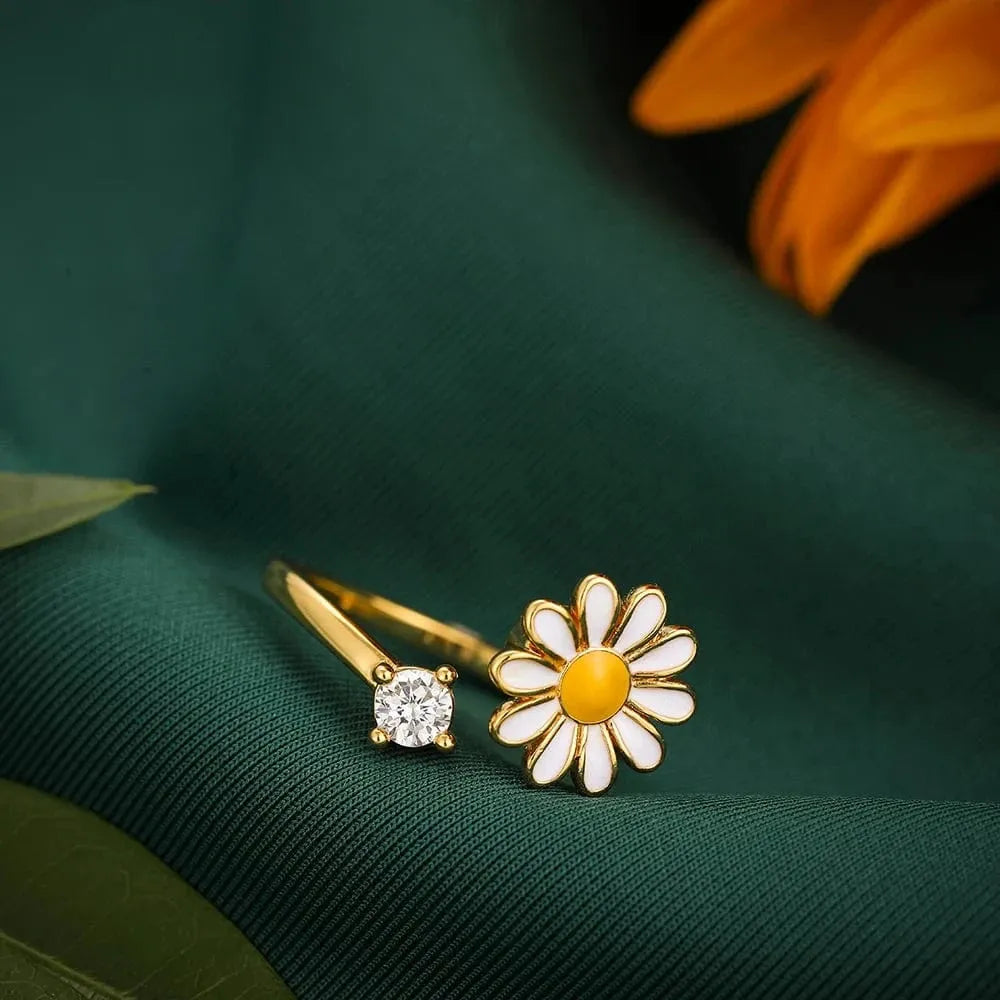 Gold ring with a diamond and a daisy-shaped earring on a green fabric background