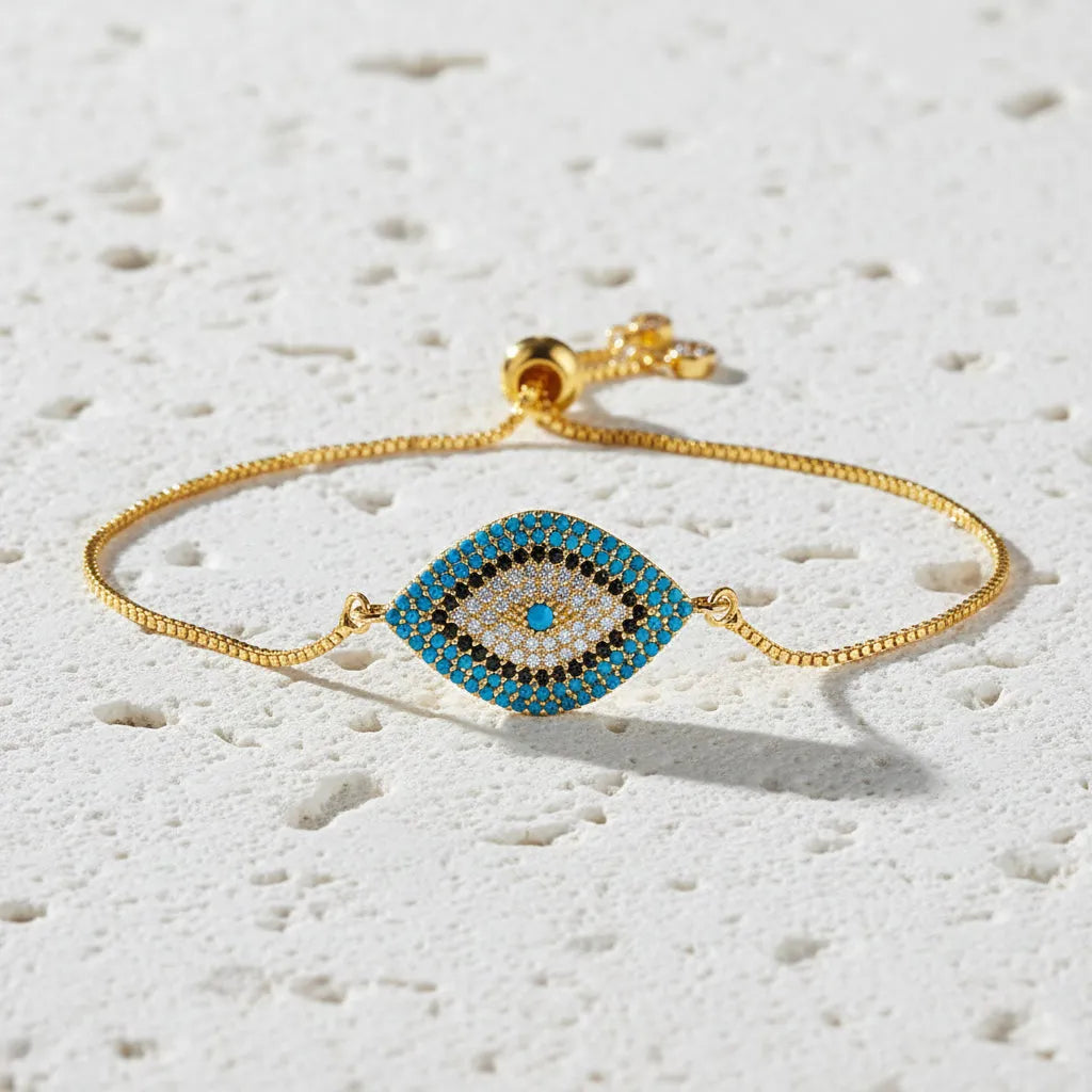 Gold bracelet with an eye-shaped charm on a dark background