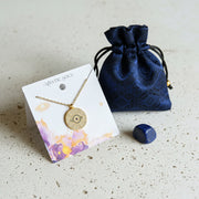 Gold pave evil eye medallion necklace with a blue eye centre and radiating sunburst rays, shown with lapis lazuli