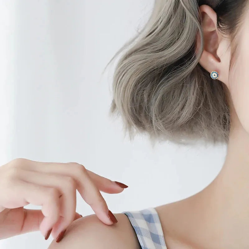 Close-up of a person wearing a evil eye earring with a plain background