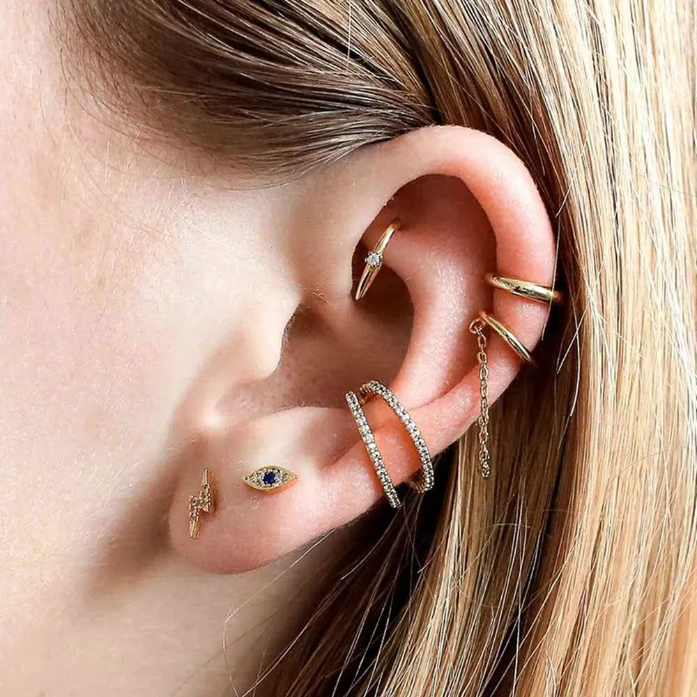 Close-up of an ear with multiple gold and silver earrings.