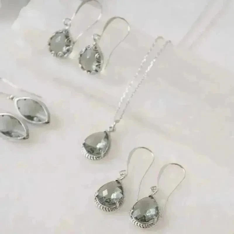 Silver earrings with clear gemstones on a light background