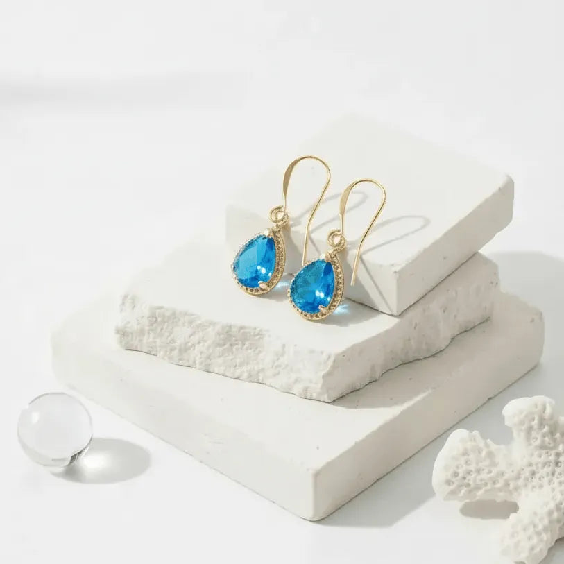 Gold earrings with blue gemstones on a white surface