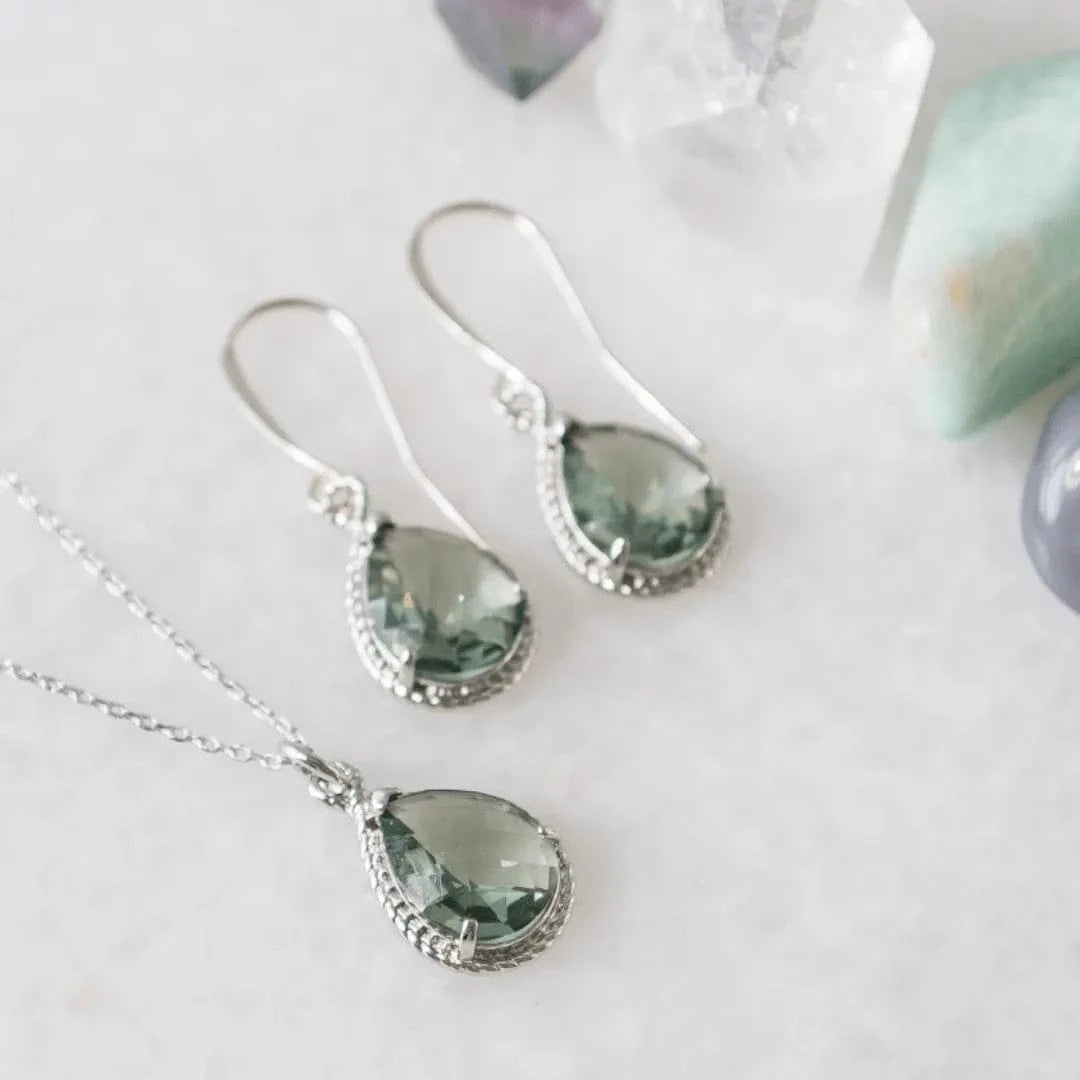 Jewelry set with green teardrop-shaped stones on a white background
