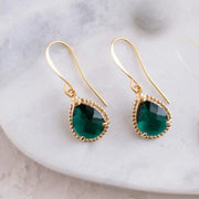 Gold earrings with green gemstones on a white surface