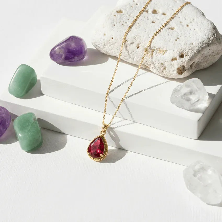 Necklace with a red pendant on a white surface with crystals and stones