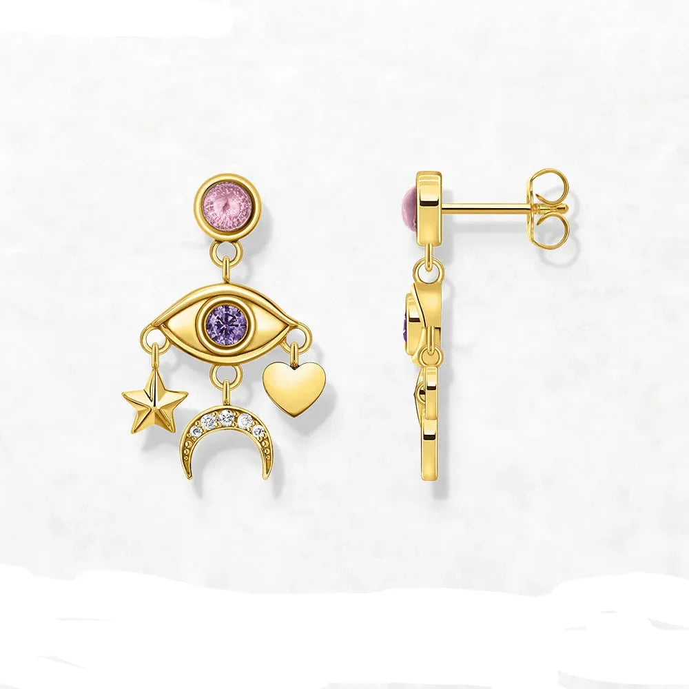 Gold earrings with eye, heart, star, and moon charms on a white background