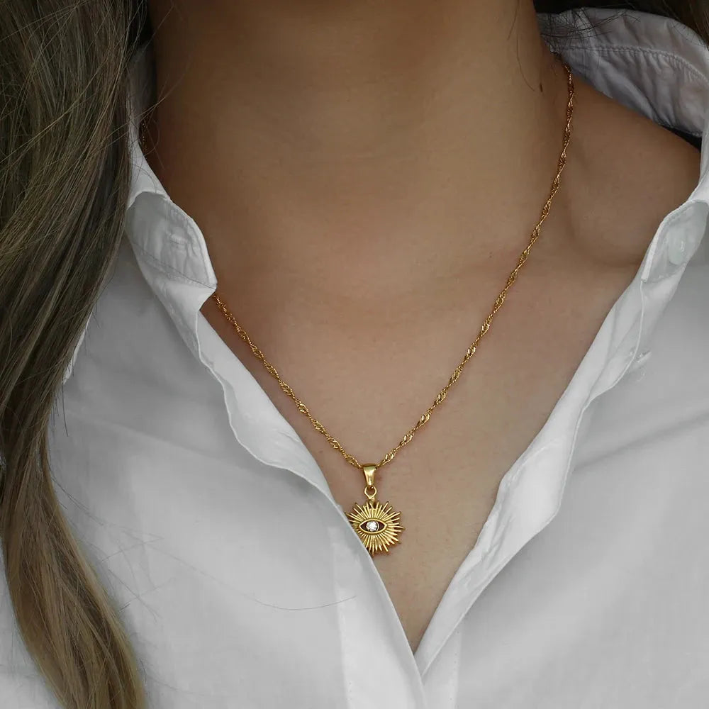Gold necklace with a pendant worn by a person in a white shirt