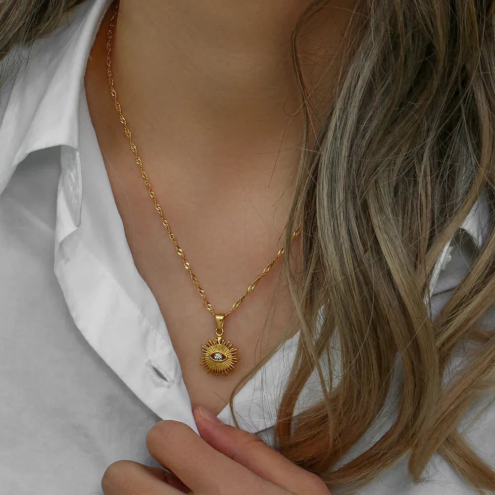 Gold necklace with a pendant worn by a person against a neutral background