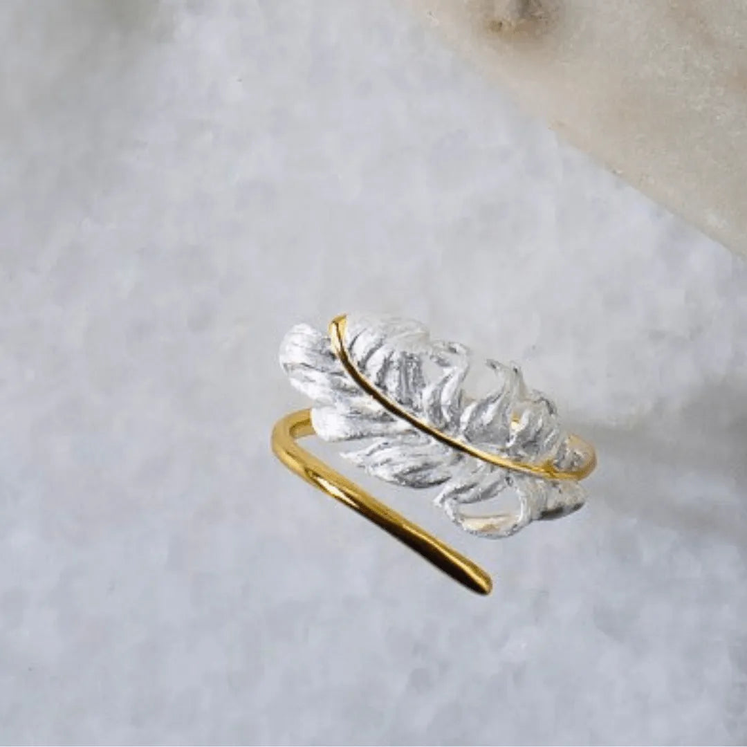 Gold and clear crystal leaf-shaped ring on a light background