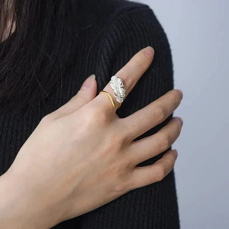 Hand wearing a gold ring with a textured design on a plain background