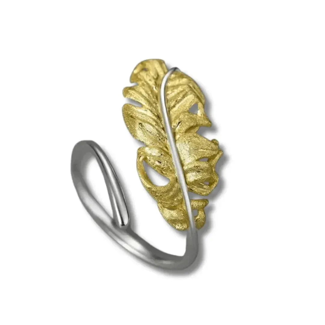 Silver ring with a gold leaf design on a white background
