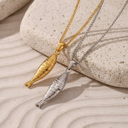 Gold and silver fish-shaped pendants on chains against a beige and white background