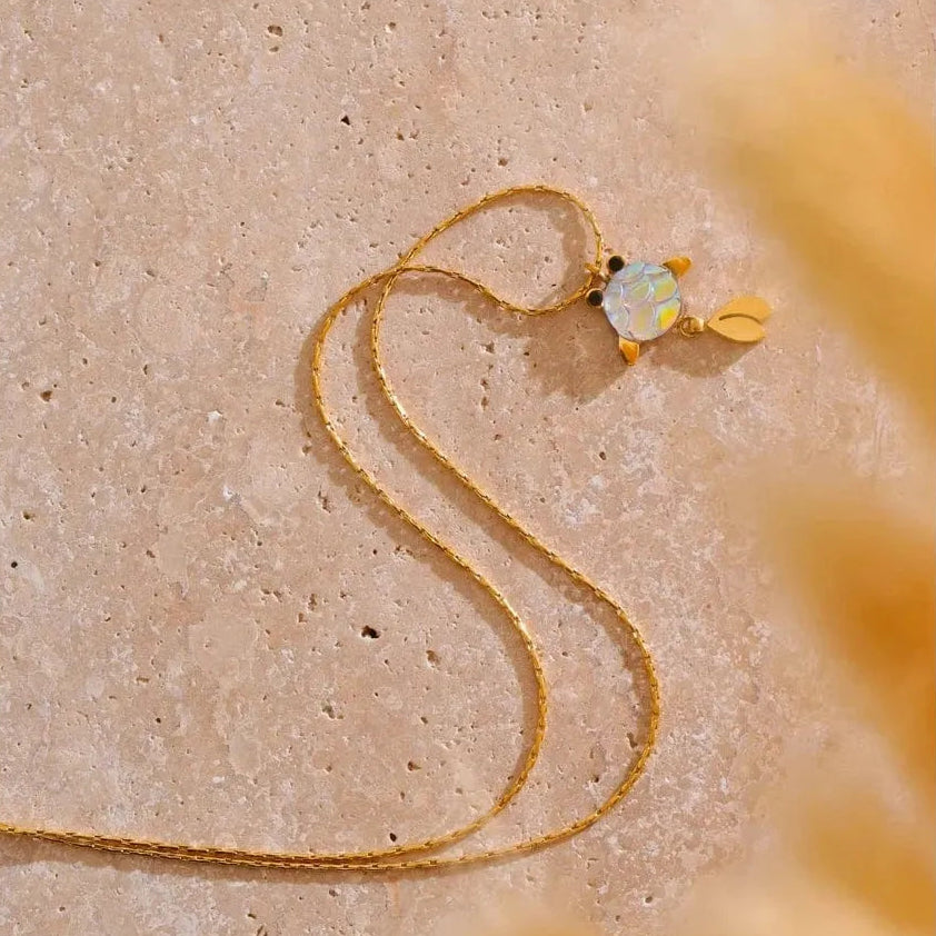 Gold necklace with a heart-shaped pendant on a beige background