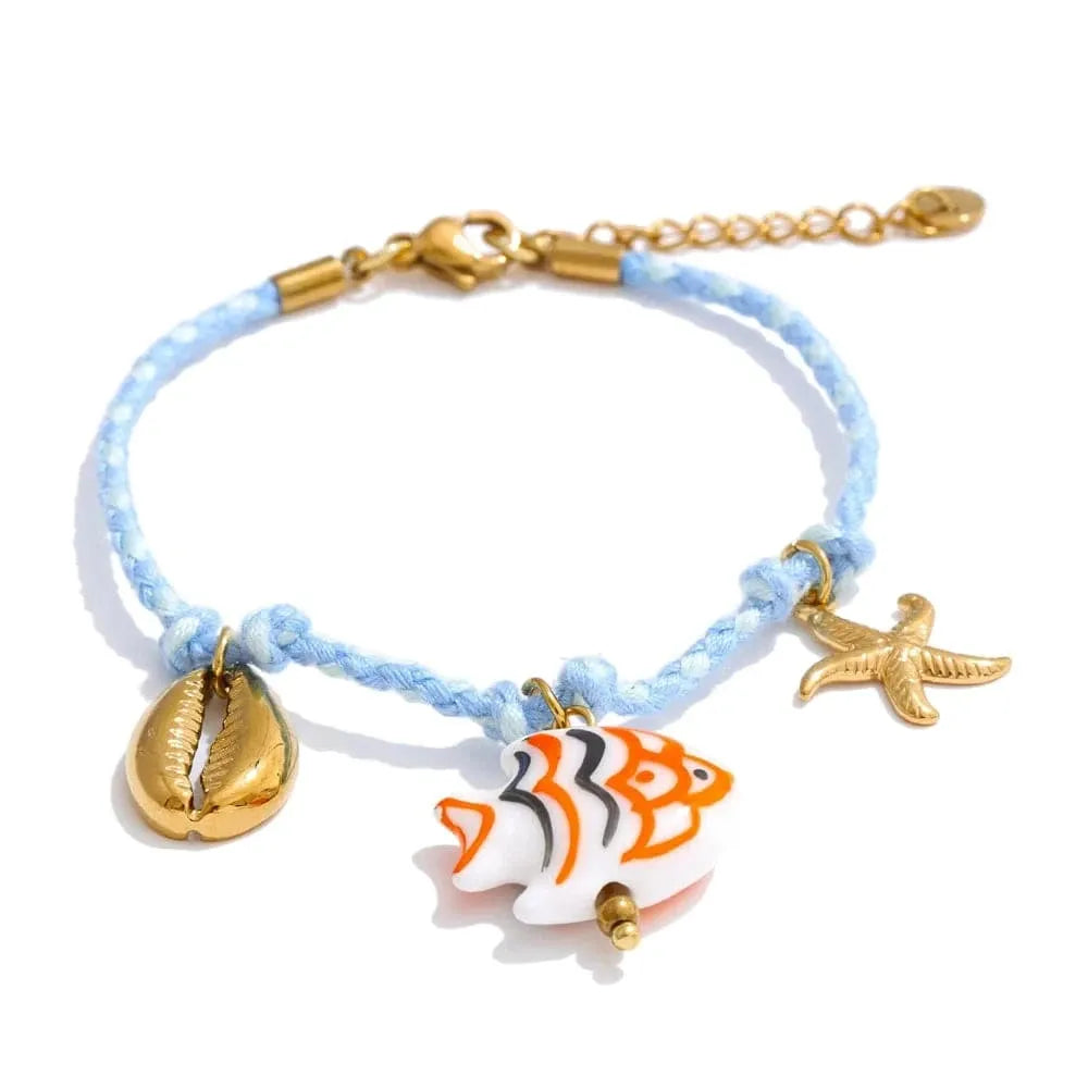 Bracelet with fish, shell, and starfish charms on a light blue cord.