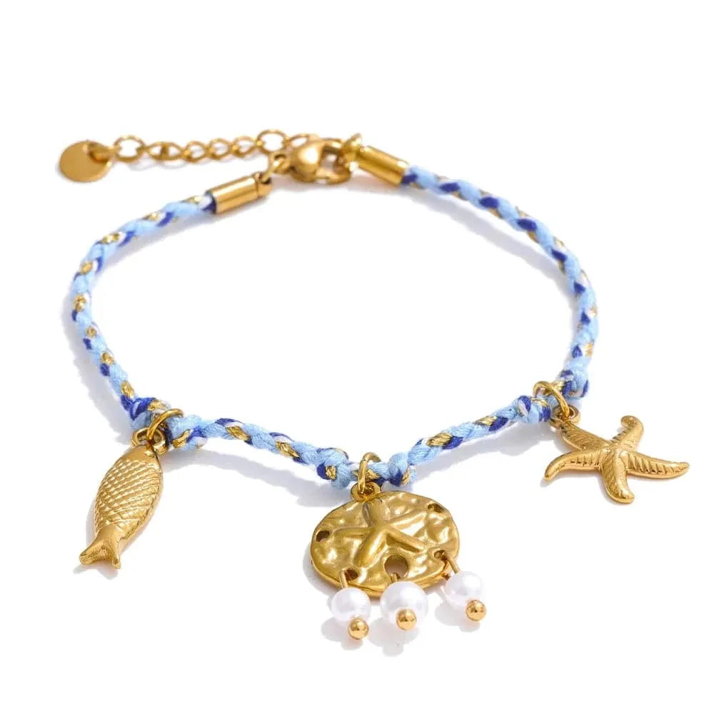 Bracelet with gold fish, sand dollar, and starfish charms on a blue and white braided cord.