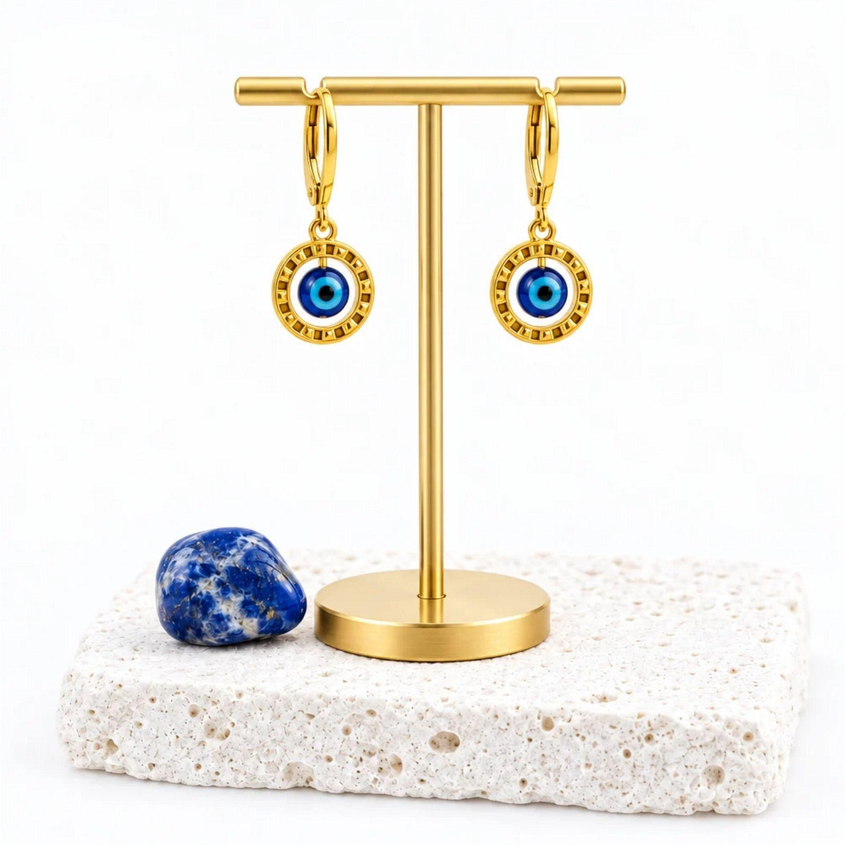 Gold floating evil eye leverback earrings hanging on a gold earring stand