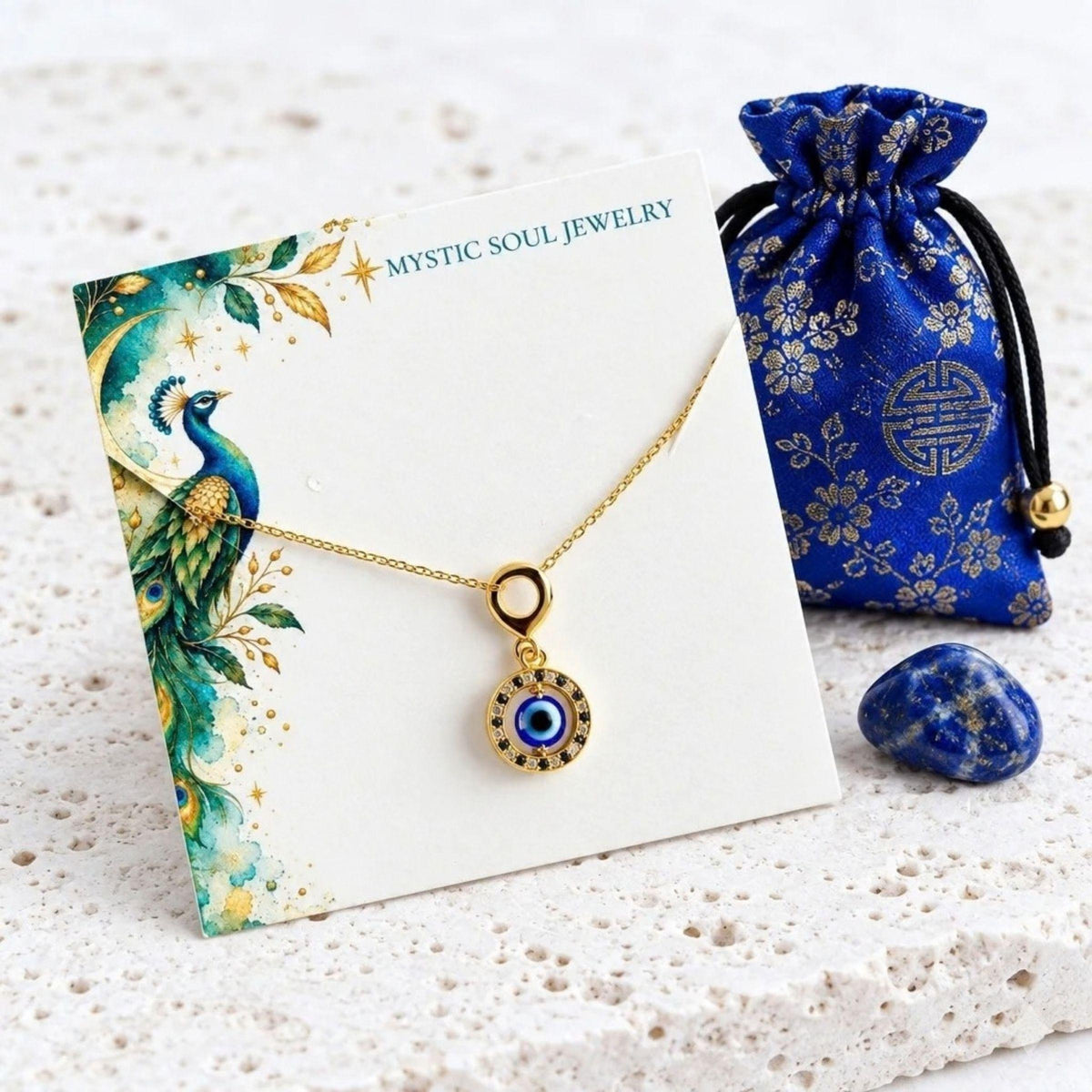 Gold floating evil eye necklace on a peacock gift card with a blue gift pouch