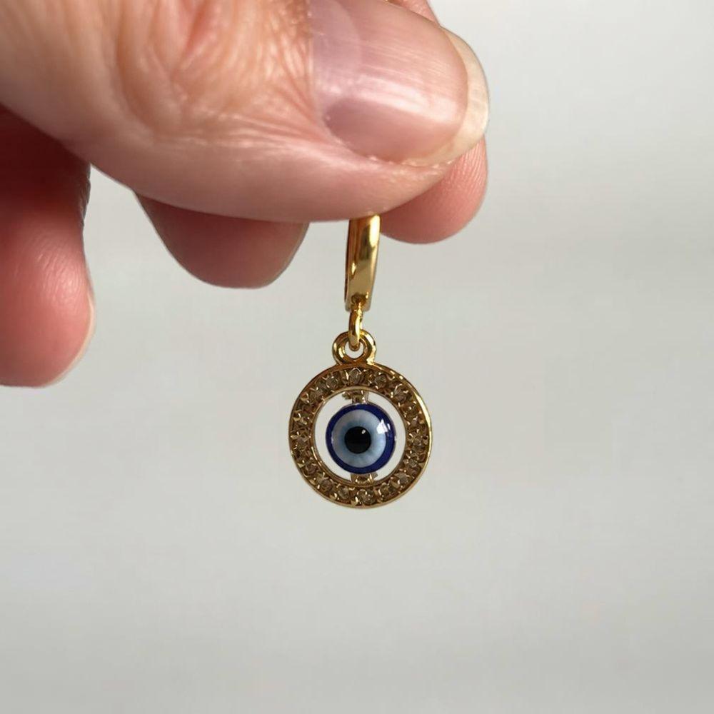 Gold floating blue evil eye pendant necklace held in hand, protection symbol jewelry