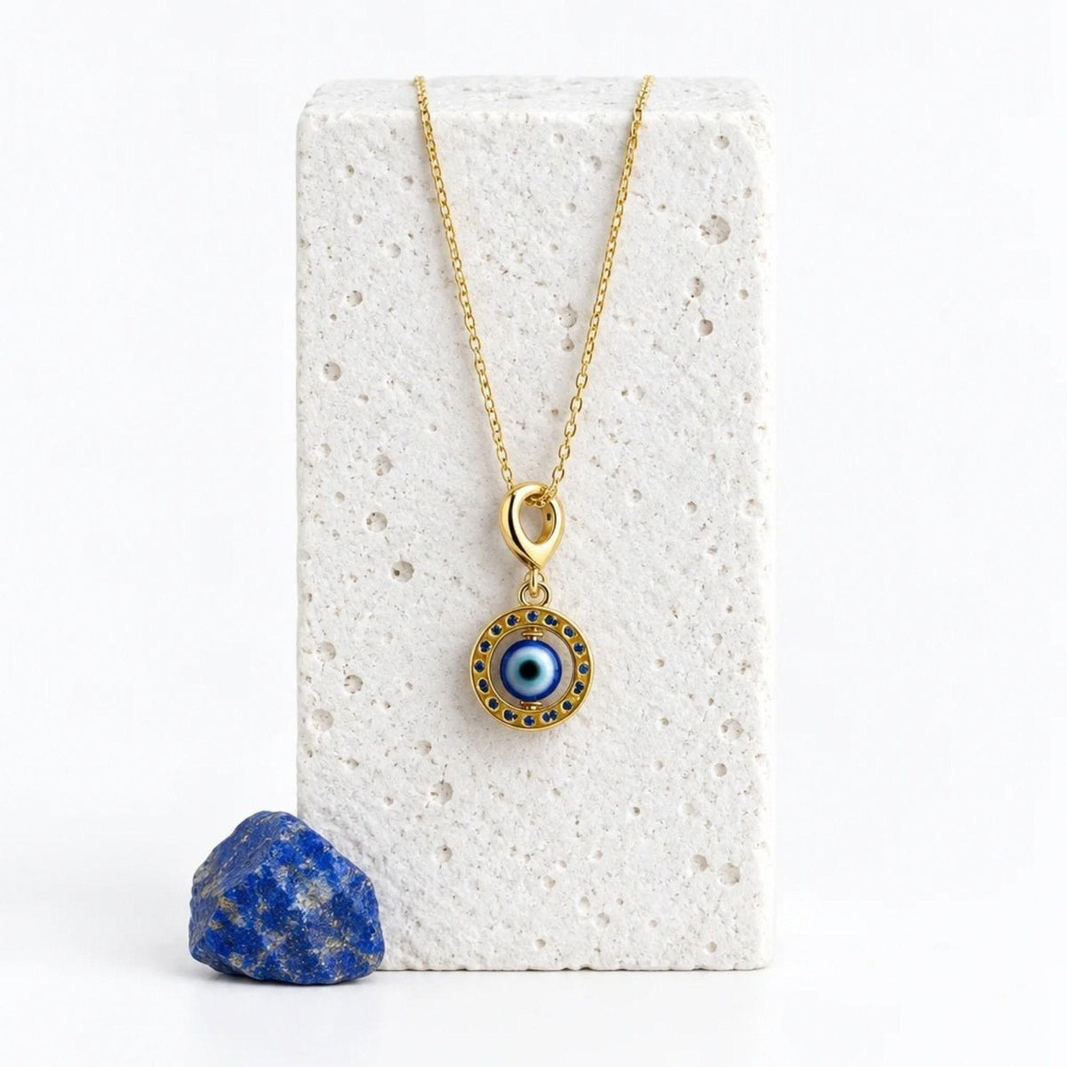 Gold floating evil eye pendant necklace on a white stand