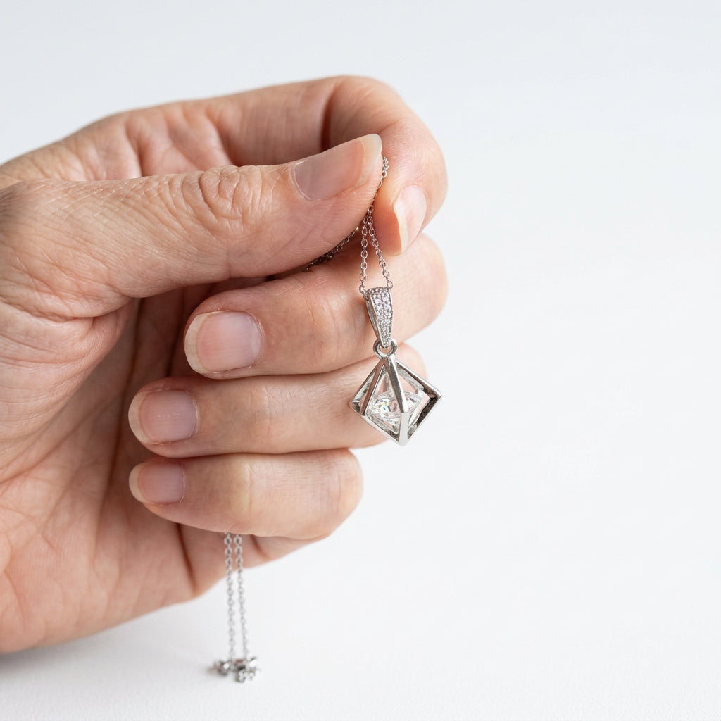 Silver Floating Prism necklace held in hand to show size, clear faceted glass bead in an open geometric frame
