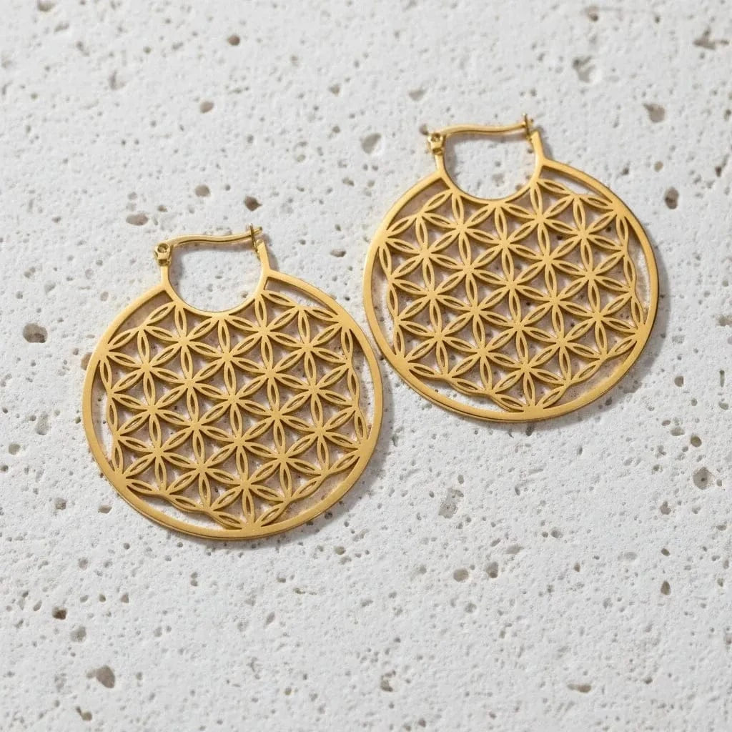Gold hoop earrings with intricate geometric design on a white stone