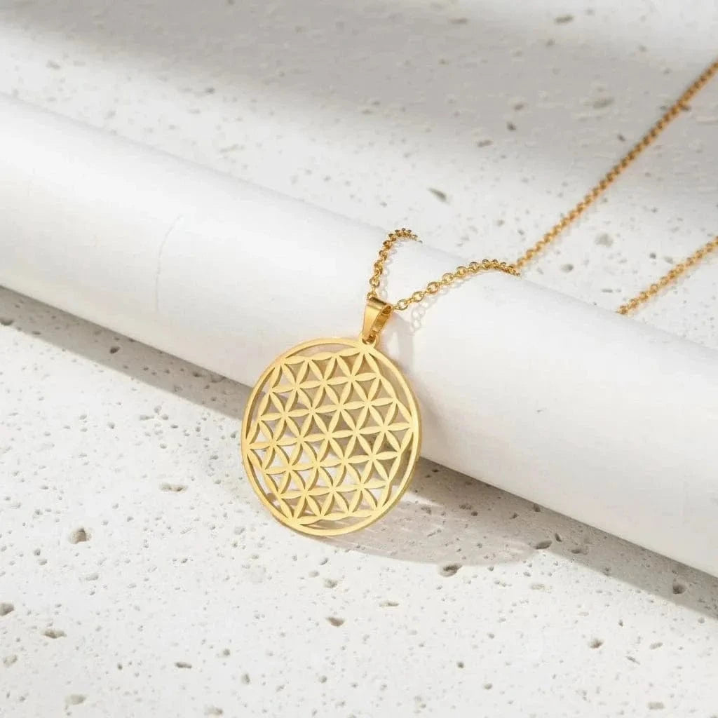 Gold geometric pendant necklace on a white cylindrical object with a green background