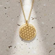 Gold necklace with a geometric pendant on a black background, branded 'Unift'.