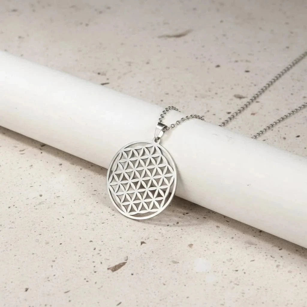 Silver geometric pendant necklace on a white cylindrical object with a green background
