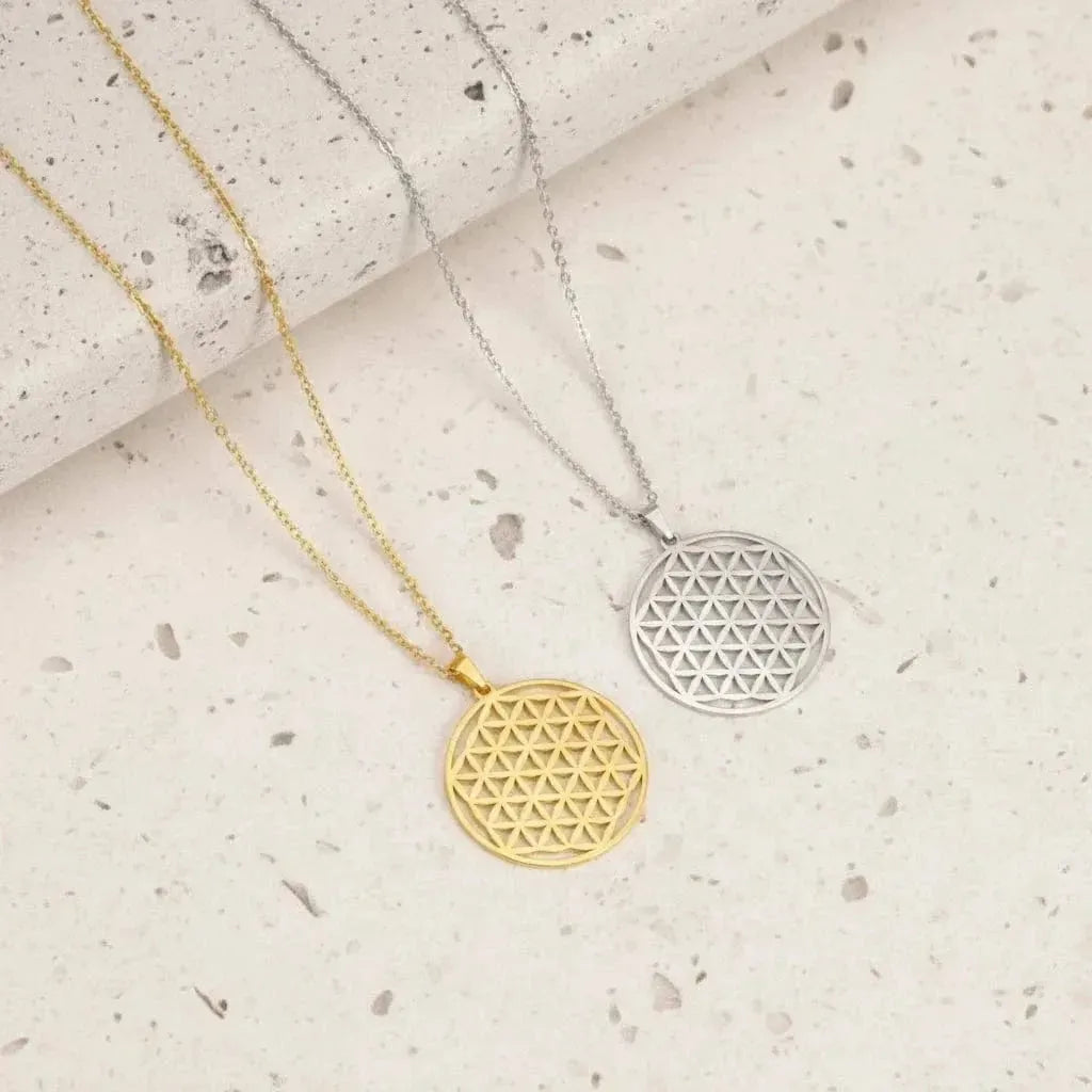 Two geometric pendants on chains against a teal background