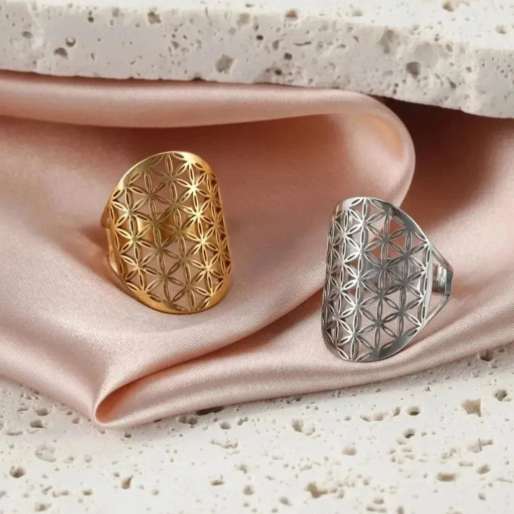 Gold and silver rings with geometric designs on a pink fabric background