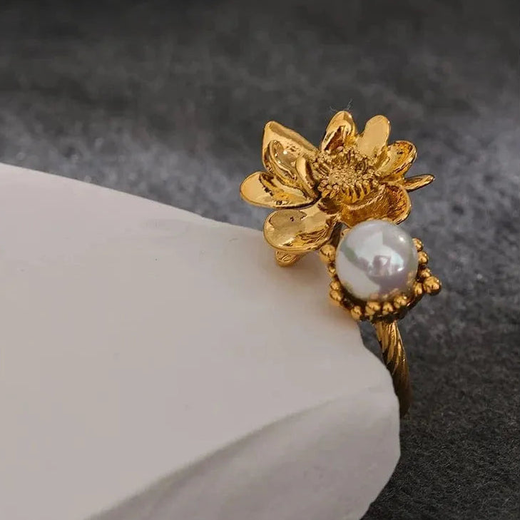 Gold flower-shaped earring with pearl on a dark background