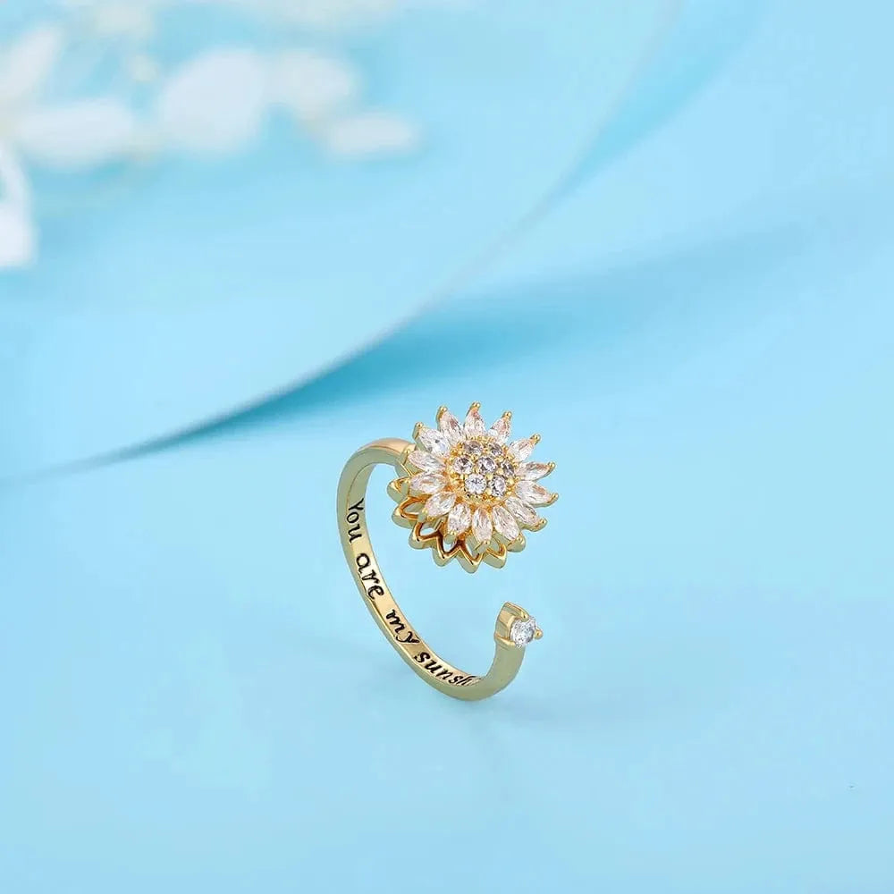 Gold open ring with sunflower design and 'You are my sunshine' engraving on a light blue background